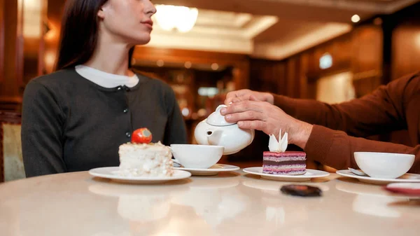 Hora del té. Foto recortada de pareja desayunando en el restaurante del hotel. El hombre está sirviendo té o café en tazas . — Foto de Stock