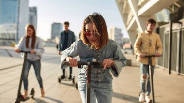 Yolların kralı olmak için doğdular. Güneşli bir günde scooter ve segway kullanan bir grup arkadaş.