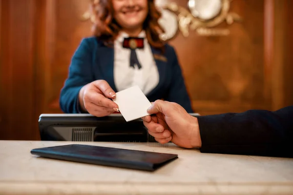 Nós convidamos você a experimentá-lo. Feche de mãos masculinas e femininas. Sorrindo recepcionista feminina atrás do balcão no hotel dando cartão-chave para o convidado . — Fotografia de Stock