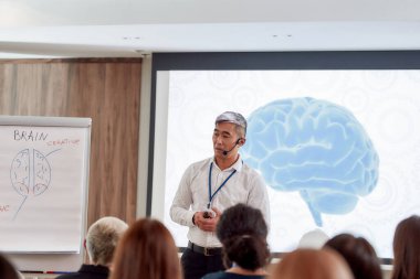 Eğitim için dengeli. Takım elbiseli, kulaklıklı ve lazerli Asyalı erkek konuşmacı şirket toplantısında konuşma yapıyor.