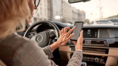 Senin için her zaman müsaidim. Arabadaki sürücü koltuğunda otururken akıllı telefonunu kullanan güzel bir iş kadınının arka görüntüsü.