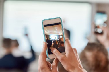 Şimdi daha fazla çıkar. Fotoğraf çekilirken akıllı telefonu tutan katılımcıların arka planı, konferans salonundaki kurumsal iş toplantısının videosu