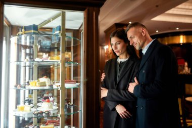 Zor bir seçim. Mutlu çift, iş adamları tatlıyı seçiyor, otel restoranında pasta yiyor.