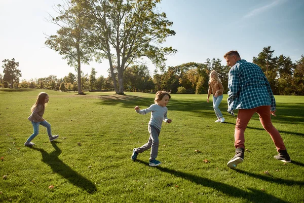 Lyckliga minnen. Spännande familj springer utomhus på en solig dag — Stockfoto