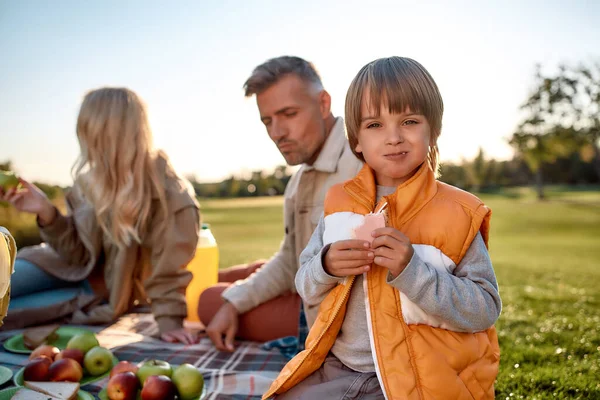 Äter tillsammans. Lycklig familj tillbringa tid i parken på en solig dag — Stockfoto