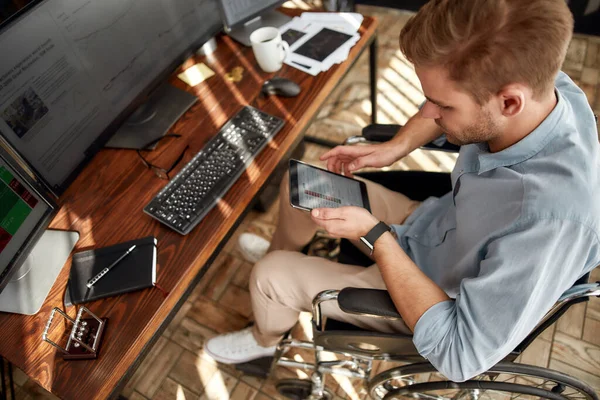 Veriler analiz ediliyor. İş yerinde çalışırken dijital tablet kullanan genç bir erkek tüccar ya da iş adamı. — Stok fotoğraf