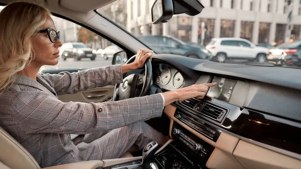 Mądry parking. Widok z boku skupienia kobieta biznesu za pomocą systemu wspomagania parkowania podczas jazdy samochodem — Zdjęcie stockowe