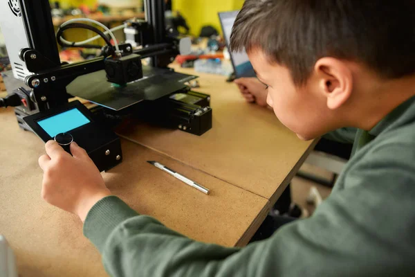 En contacto con el mañana. Primer plano de niño curioso aprender más sobre el principio de funcionamiento de la impresora 3D en la clase de robótica. Tecnología aditiva moderna progresiva. 4ª revolución industrial . — Foto de Stock