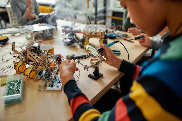 No es imposible. Recortado tiro de joven ingeniero utilizando soldador para unir chips y cables. Robótica e ingeniería de software para estudiantes de primaria. Invenciones y creatividad para niños —  Fotos de Stock