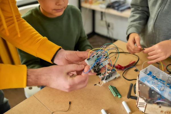 Problem solved. Close up of electronic circuit board. Young technicians working with a wiring kit together with a male teacher at a stem robotics class. Inventions and creativity for kids — Stock Photo, Image