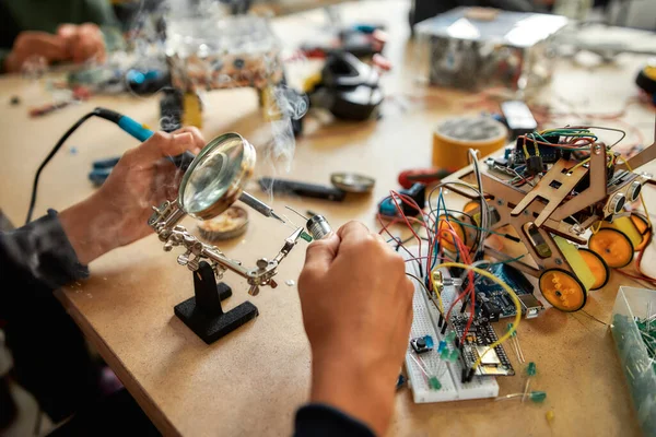 Passion möter framtid. Närbild av unga ingenjör som använder lödjärn för att ansluta chips och trådar. Robotteknik och programvaruteknik för grundläggande studenter. Uppfinningar och kreativitet för barn — Stockfoto