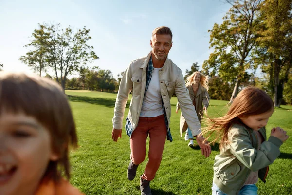 Härlig helg. Spännande familj springer utomhus på en solig dag — Stockfoto