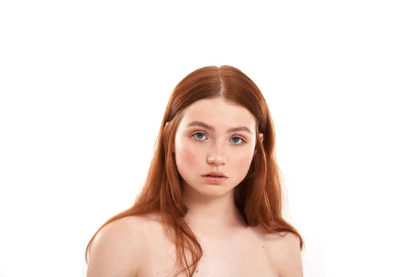 Природна краса. Крупним планом портрет молодої і привабливої рудоволоса дівчина з веснянками дивиться на камеру, стоячи на білому тлі — стокове фото
