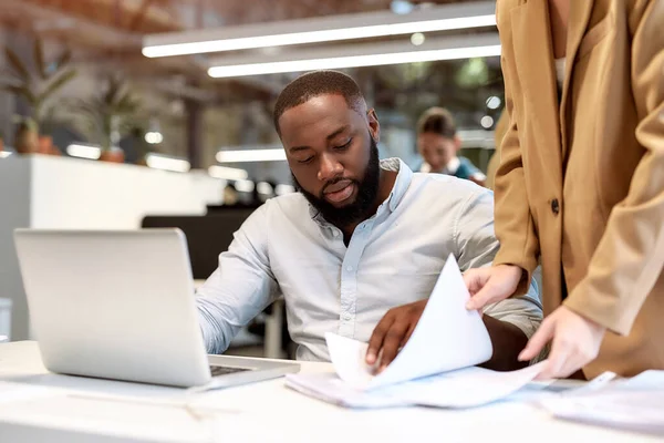 Gut gemacht. Junger Afroamerikaner diskutiert Projektberichte mit seinem Kollegen, während er gemeinsam im modernen Büro arbeitet — Stockfoto