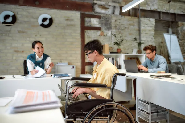 エネルギー、アイデア、空間を共有する。オフィスで働いてる車椅子の男 — ストック写真