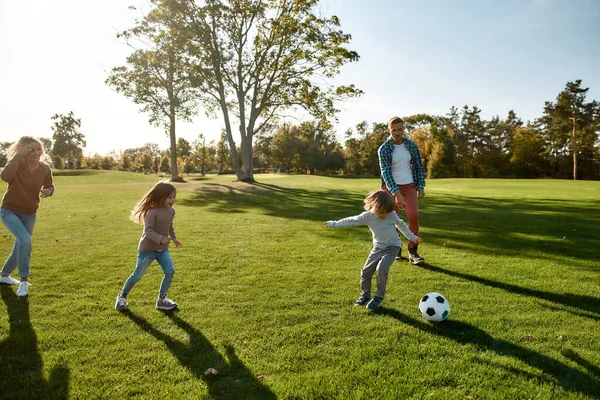 Biz futbol takımıyız. Mutlu aile çayırda top oynuyor. — Stok fotoğraf
