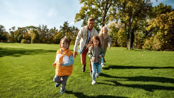 Härlig dag. Spännande familj springer utomhus på en solig dag — Stockfoto