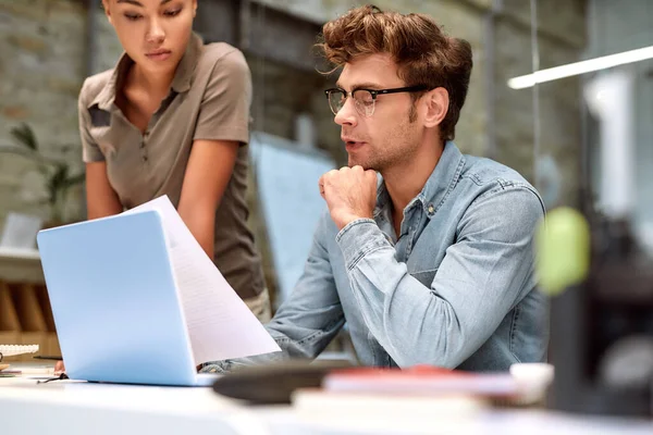 Insieme possiamo fare molto. Giovani colleghi che guardano il documento e discutono qualcosa mentre lavorano insieme nell'ufficio creativo — Foto Stock