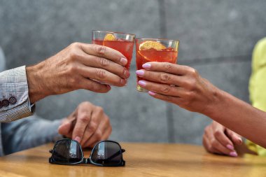 Şerefine. Erkeklerin ve kadınların elleri kafede otururken kokteyl tutuyorlar.