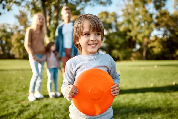 Víkend spolu. Malý chlapec hraje frisbee v parku za slunečného dne — Stock fotografie