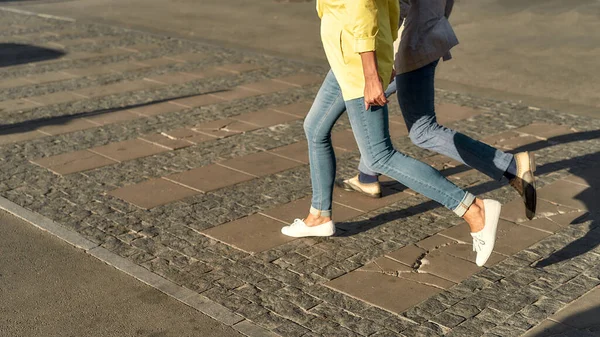 Cropped photo of a couple in casual clothes running across the street — Stock Photo, Image