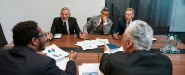 Çok kültürlü hayal kırıklığına uğramış iş adamları modern ofisteki ortaklarla toplantı yaparken bir şeyler tartışırken resmi kıyafetlerini giyerler.