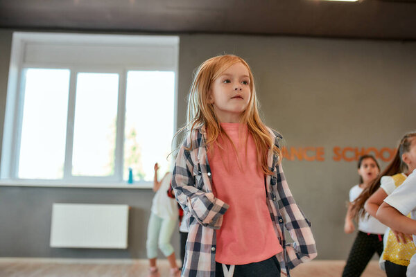 Dancing child. Portrait of a little cute girl in fashionable clothes dancing while having a choreography class. Group of children studying in the dance school