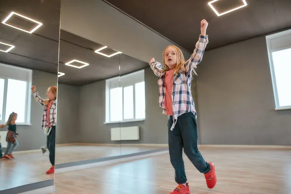 Värmer upp. En söt liten flicka som sträcker upp händerna medan hon har koreografi i studion. Dansskola — Stockfoto