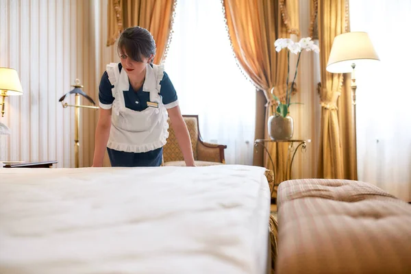 Rápido e limpo. Empregada de hotel em roupa de cama uniforme e fazendo cama em quarto de hotel de luxo. Conceito de serviço de quarto . — Fotografia de Stock