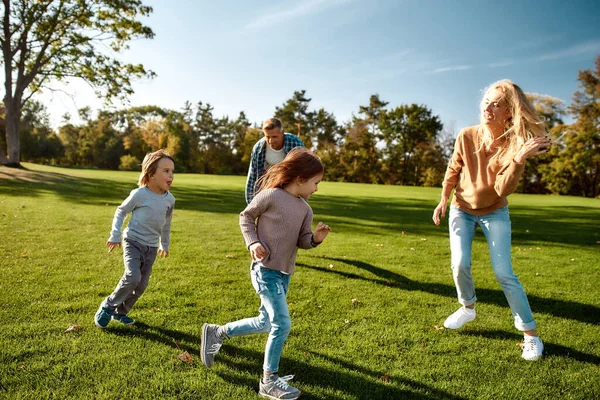 Ahol a gondozás és a játék kéz a kézben jár. Izgatott család szórakozás szabadban egy napsütéses napon — Stock Fotó