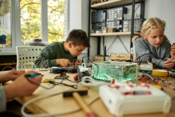 Tú lo sueñas, yo lo hago. Ingeniero joven usando soldador para unir chips y cables. Robótica e ingeniería de software para estudiantes de primaria. Invenciones y creatividad para niños —  Fotos de Stock