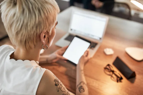 Donna d'affari moderna. Giovane donna tatuata con taglio di capelli corto utilizzando tablet digitale mentre seduta sul posto di lavoro. Donna d'affari al lavoro — Foto Stock