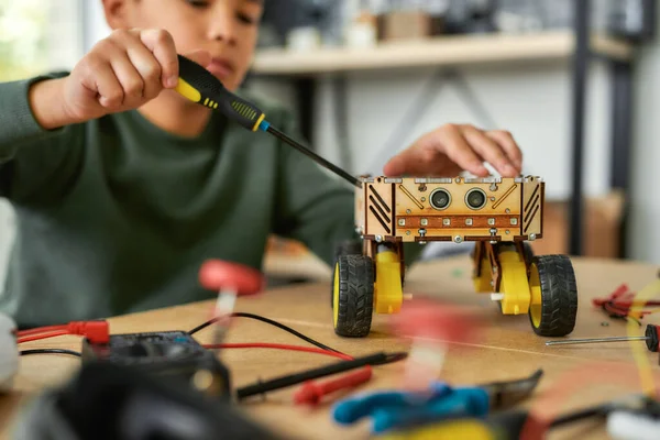 Mejorándolo. Primer plano de un niño usando destornillador mientras fija pernos en un vehículo robot. Niños inteligentes y educación STEM . — Foto de Stock