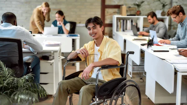 Zelfstandig werken, samen. Man in een rolstoel aan het werk in het kantoor — Stockfoto