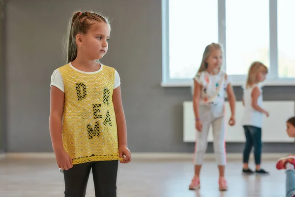 Porträtt av en liten söt flicka som tittar bort medan hon har en koreografi klass. Grupp av barn som står i dansskolan — Stockfoto