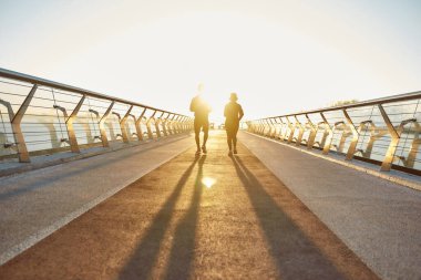 Gün doğumuna doğru. Erkek ve kadın dışarıda koşuyor. Genç, sağlıklı ve sportif çiftin sabahın erken saatlerinde köprüde birlikte koştuğunu görüyorum. Tam uzunluk