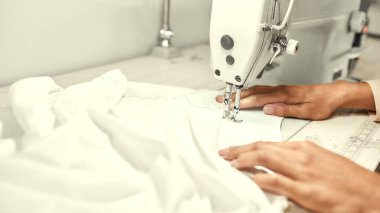 Özel Dikiş İhtiyacı. Terzinin ellerini kapat. Oturuyor ve dikiş dikiyor. Dikiş makinesinde çalışan bir terzi. İş yerinde terzi elbisesi dikiyor.