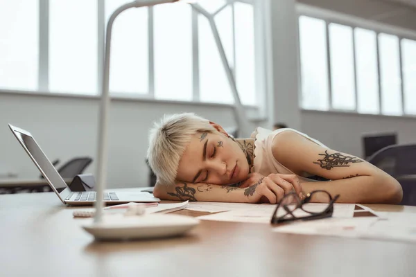 Sıkı çalışma gününden sonra. Genç ve yorgun bir iş kadını. Kısa saçlı. Çalışma masasında uyuyor. — Stok fotoğraf