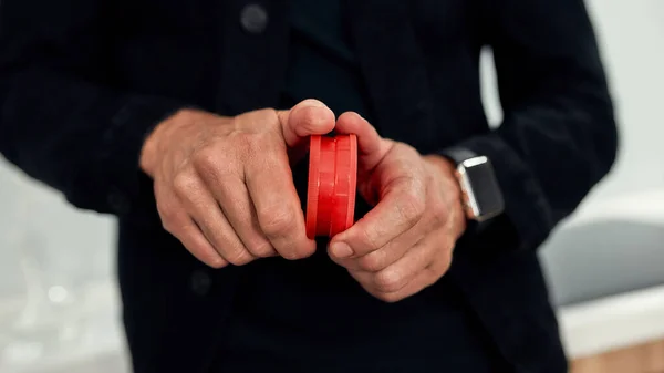 Närbild på händerna. Man använder röd marijuana kvarn, när man står i köket. Cannabis och ogräslegalisering — Stockfoto