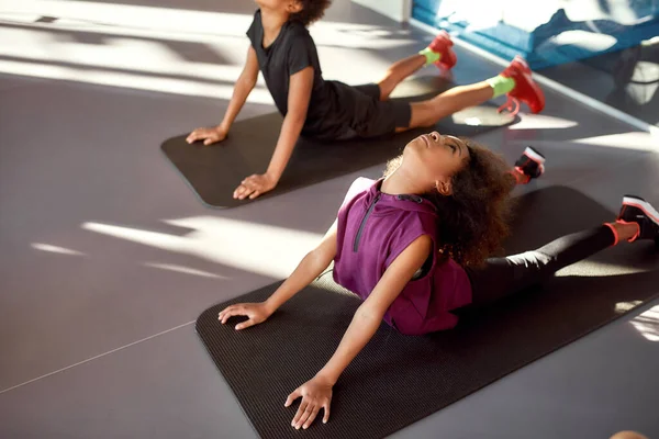 Verbeter jezelf. Portret van tiener meisje proberen yoga pose, doen oefeningen samen met andere kinderen in de sportschool. Uitrekken op een zonnige dag. Sport, gezond leven, lichamelijke opvoeding — Stockfoto