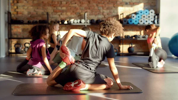 Mantenha seu corpo saudável. Tiro completo de menino tentando pose de ioga, fazendo exercícios com outras crianças e treinador feminino no ginásio. Alongamento em um dia ensolarado. Esporte, vida saudável, conceito de educação física — Fotografia de Stock