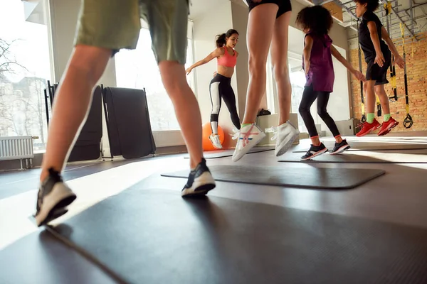 Divertido fitness definido. Tiro recortado de treinadora se exercitando com adolescentes, meninos e meninas no ginásio. A aquecer num dia ensolarado. Esporte, estilo de vida saudável, conceito de educação física — Fotografia de Stock