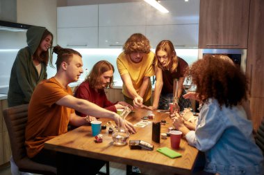 Bir grup arkadaş evde mutfakta birlikte otururken poker oynayıp marihuana içiyor. Marihuana aletleri, masada nargile.
