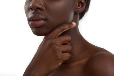 Mükemmel koyu ten. Beyaz arka planda duran büyük doğal dudaklı Afrikalı genç bir kadının kesilmiş fotoğrafı. Koyu ten modeli