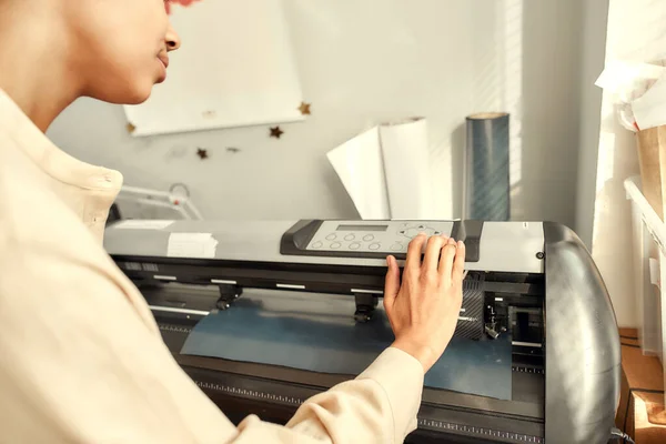 Impresión maestra. Imagen recortada de una mujer joven controlando, monitoreando la máquina de impresión mientras imprime una etiqueta publicitaria con texto o imagen para una camiseta — Foto de Stock