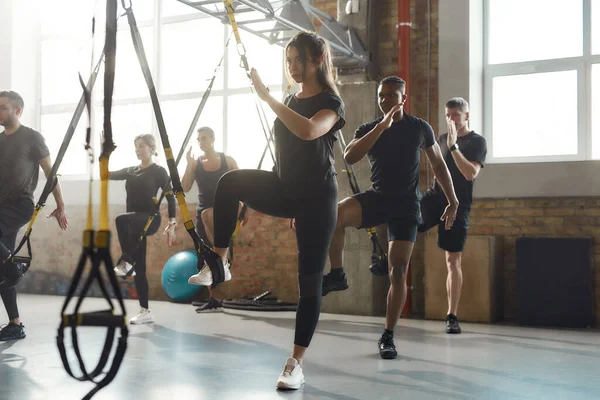 Solo risultati. Colpo completo della donna caucasica messa a fuoco che fa gli esercizi di addestramento di idoneità TRX al gym industriale. Cinghie, concetto di allenamento di gruppo — Foto Stock