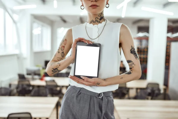 Sto mostrando un nuovo gadget. Foto ritagliata di donna d'affari tatuata con tablet digitale in piedi in un moderno spazio di coworking — Foto Stock