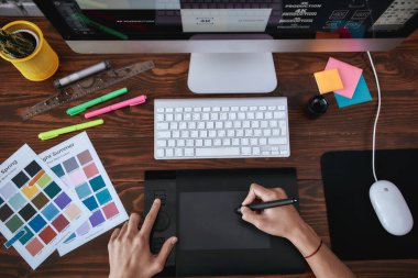Doğru ekipman. Grafik tablet kullanan ve ofisteki iş yerinde otururken bilgisayarla çalışan bir tasarımcının üst görüntüsü. Grafik tableti, klavyesi ve bilgisayarı olan bir iş yerinin üst görünümü.