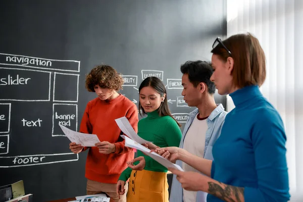 Jovens profissionais. Grupo de quatro web designers em desgaste casual desenvolver novo layout web site, tendo uma reunião no escritório moderno — Fotografia de Stock