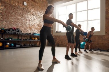 Almak için mücadele et. Endüstriyel spor salonunda egzersiz yaparken ağırlık kaldıran bir grup sporcu. Grup eğitimi, takım çalışması konsepti